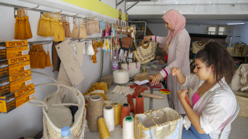 Women work at Tunisian designer Siraz Badis' workshop in eastern Tunisian city of Beni Khiar on August 12, 2022. Badis works on traditional purses, made of palm trees, adding her own designs before they can be used for market and bazaar shopping. (Photo by Yassine Gaidi/Anadolu Agency via Getty Images)