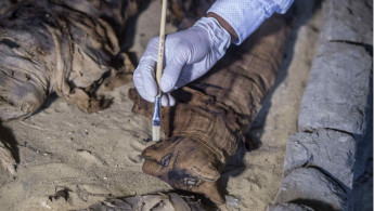 An Egyptian archaeologist cleans mummified south of Cairo