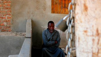 nubian man sits outside house