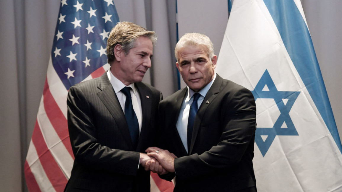 Antony Blinken (left) with Yair Lapid (right) against a backdrop of the US and Israeli flags