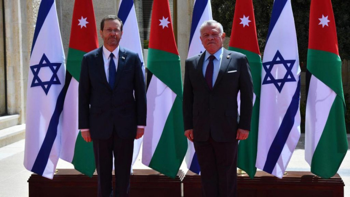 Isaac Herzog (left), Israel's president, stands next to Jordan's King Abdullah (right), in front of a backdrop of Israeli and Jordanian flags
