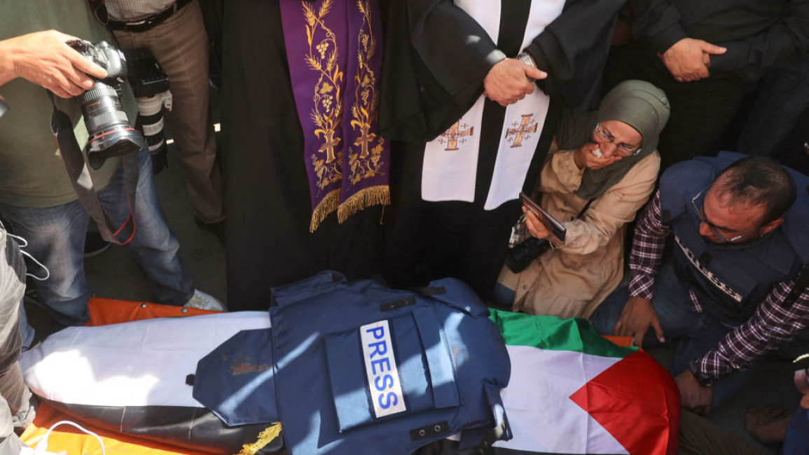 The body of Palestinian journalist Shireen Abu Akleh covered in a press vest and Palestinian flag.