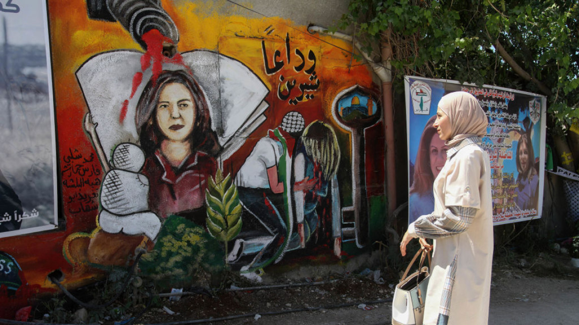 A woman standing in front of a mural to Shireen Abu Akleh at the location the Palestinian journalist was killed by Israeli forces.