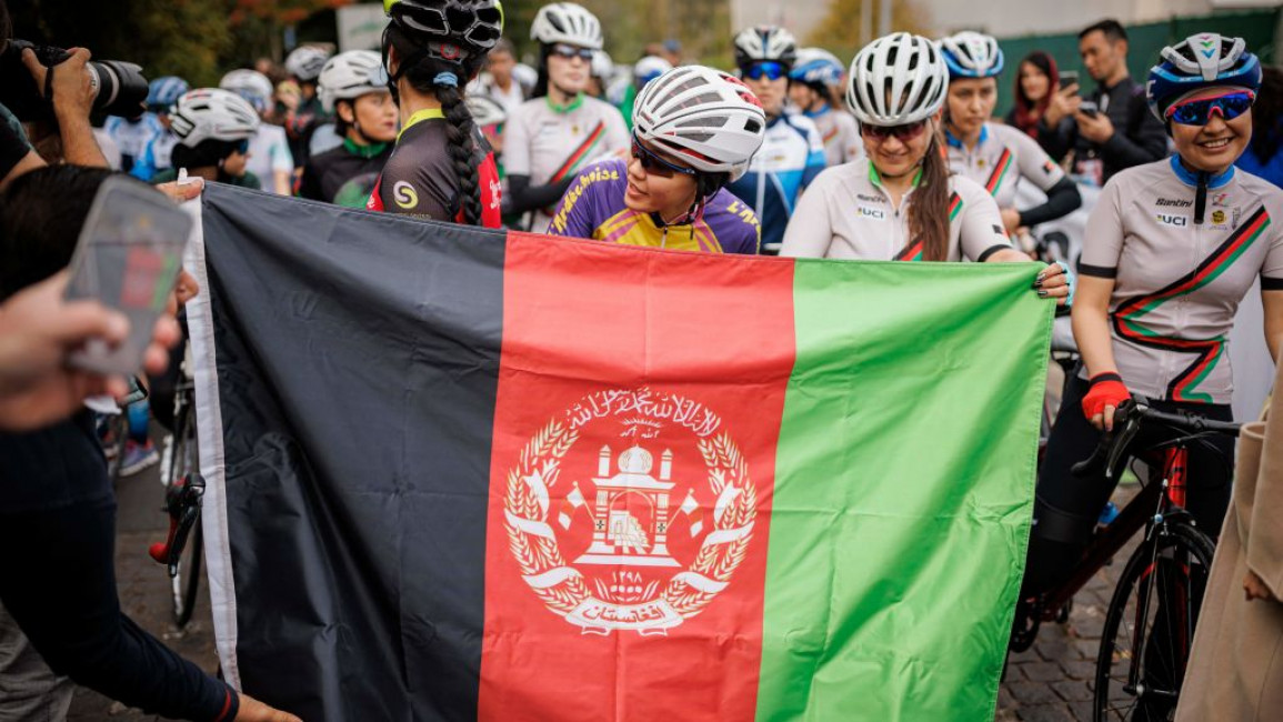 An Afghanistan flag in front of Afghan woman cyclist Masomah Ali Zada