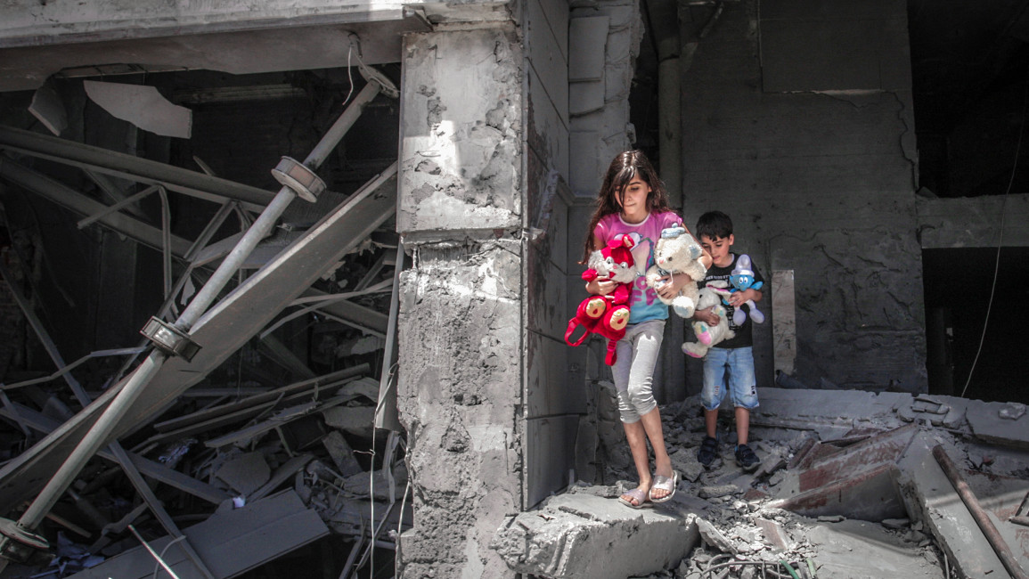 Palestinian children salvage toys from their home at the Al-Jawhara Tower in Gaza City
