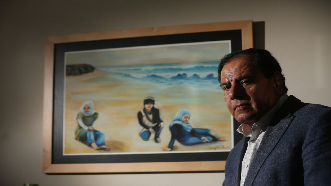 Izzeldin Abuelaish stands in front of a painting of his 3 daughters killed in 2009