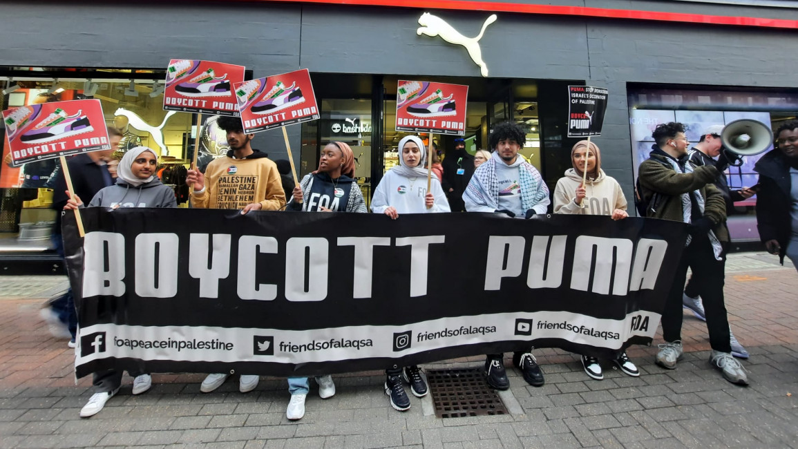 Protesters holding a "Boycott PUMA" banner outside a PUMA shop