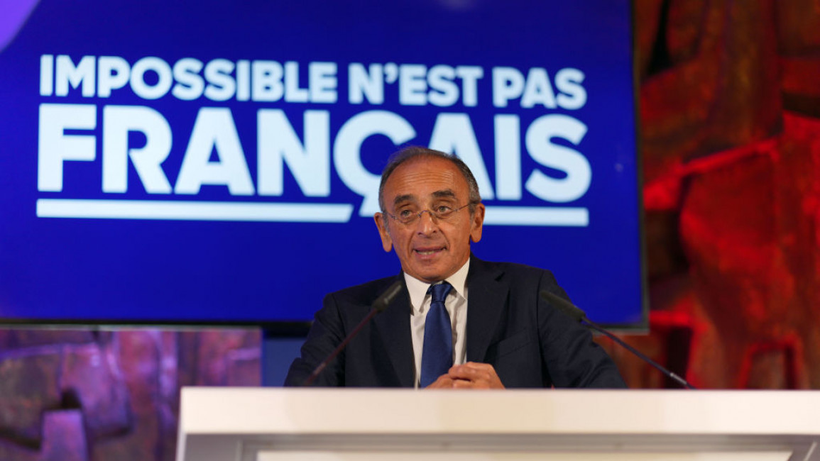 Eric Zemmour at a podium, behind a sign reading, "Impossible is not French" in French