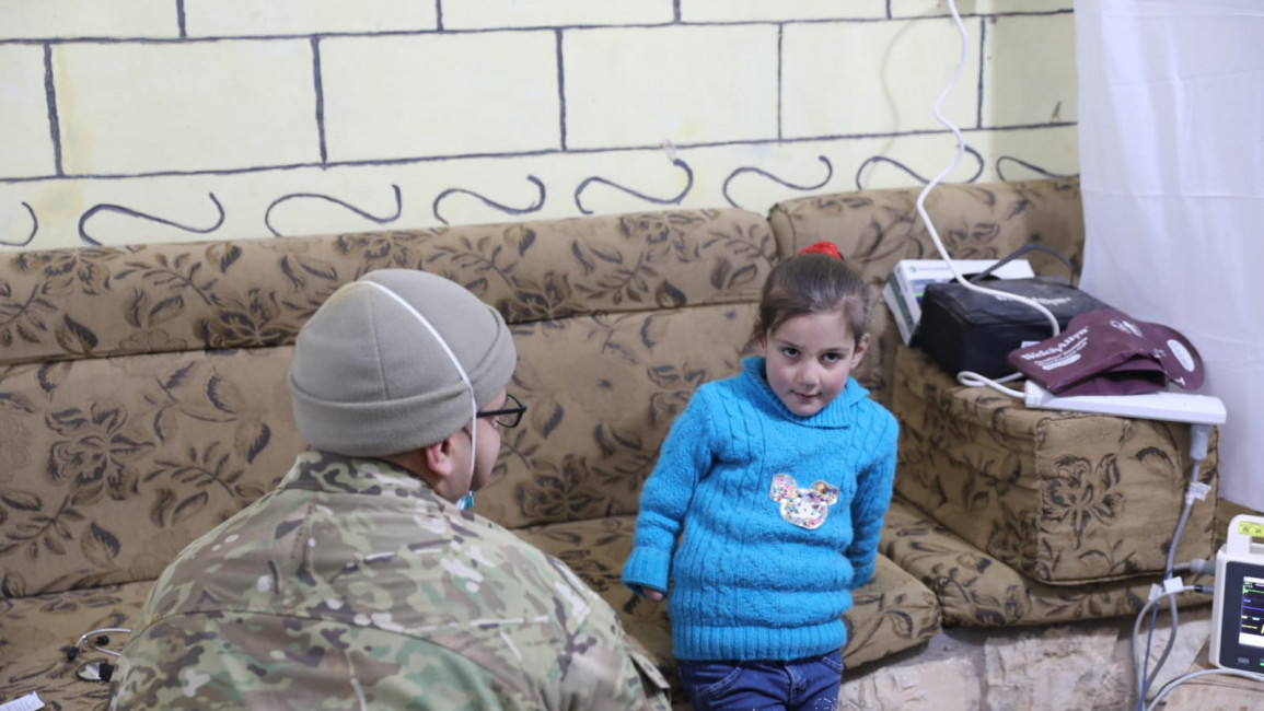 A member of Syrian opposition faction Maghawir al-Thawra (MaT) sits with a child. (Image provided by MaT).