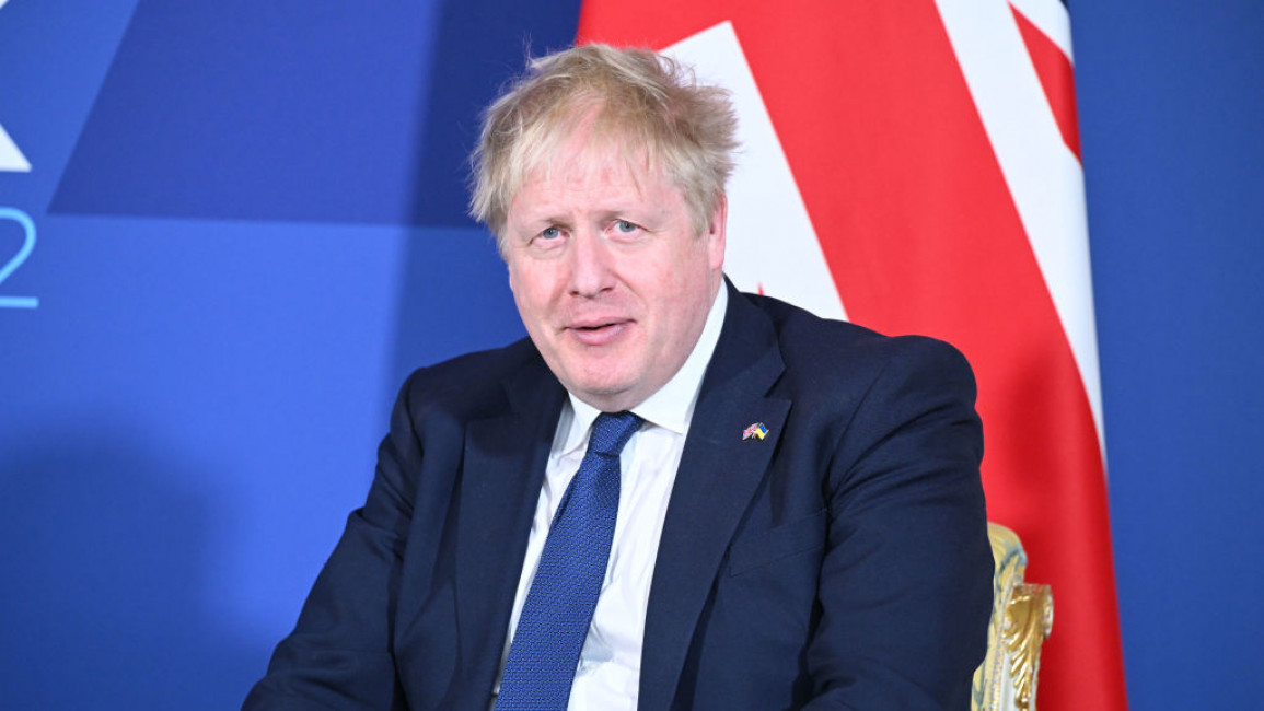 UK Prime Minister Boris Johnson sitting in front of a British flag