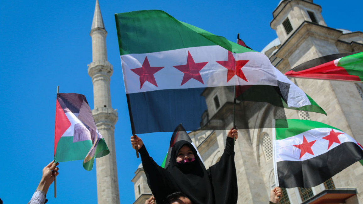 Protesters wave the Free Syrian Army and Palestinian flags while shouting slogans during the demonstration.