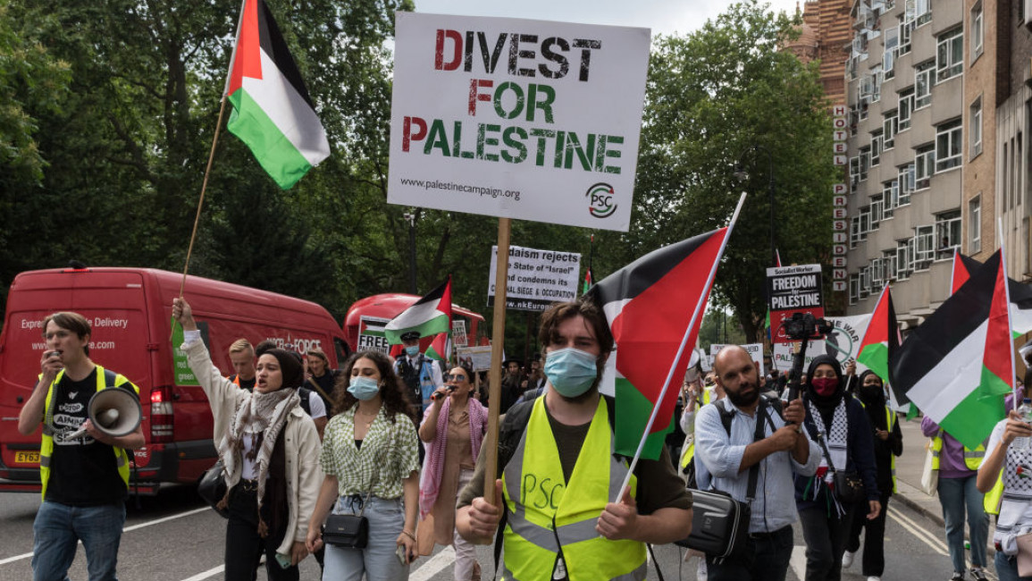 Protesters marching in London, with one holding a sign reading: "Divest for Palestine."