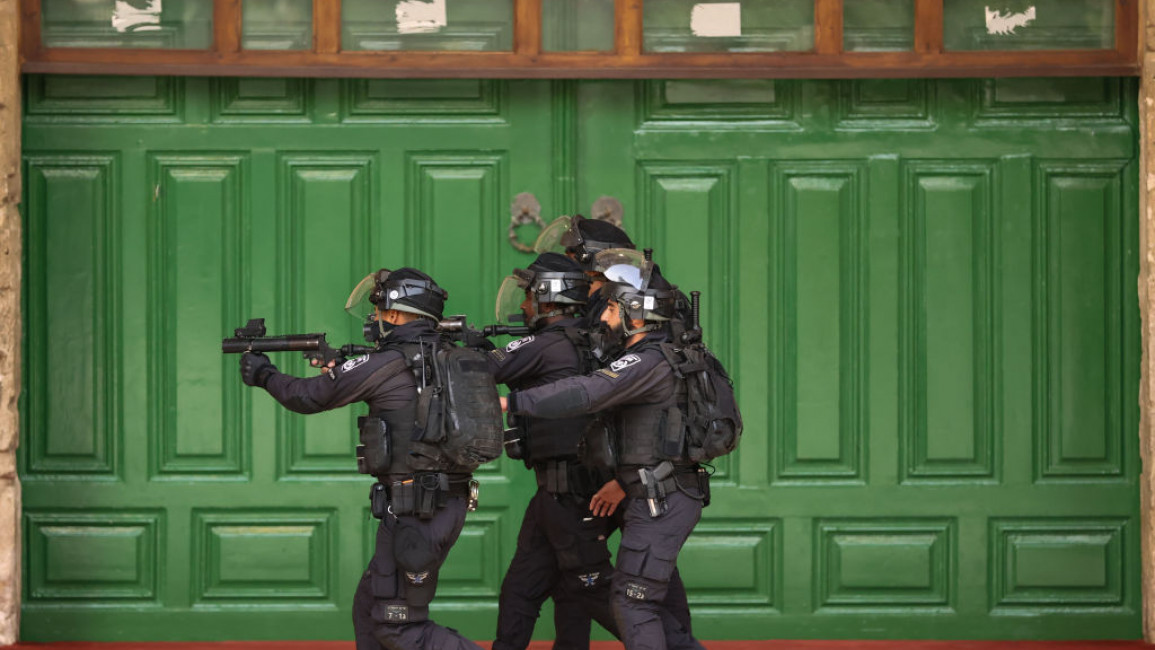 Three Israeli police officers against the backdrop of green doors at the Al-Aqsa Mosque compound