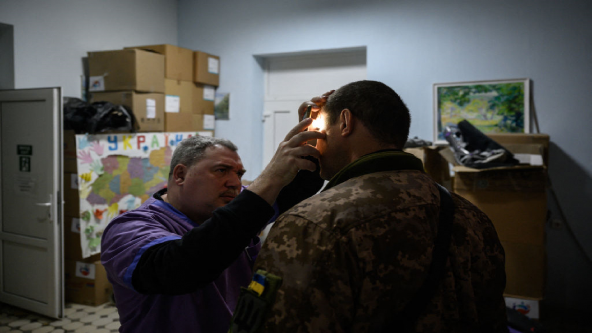 A medical staff member checks the eyes of a Ukrainian soldier