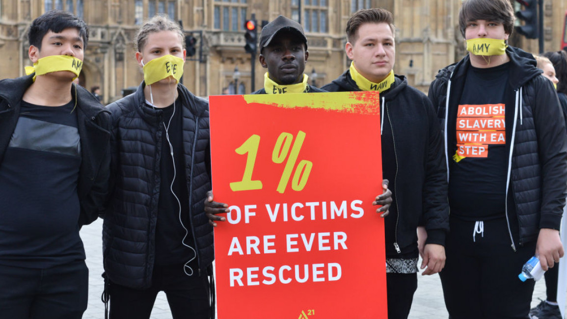 People marching against modern slavery through London wearing face masks representing the silence of modern slaves in forced labour and sexual exploitation