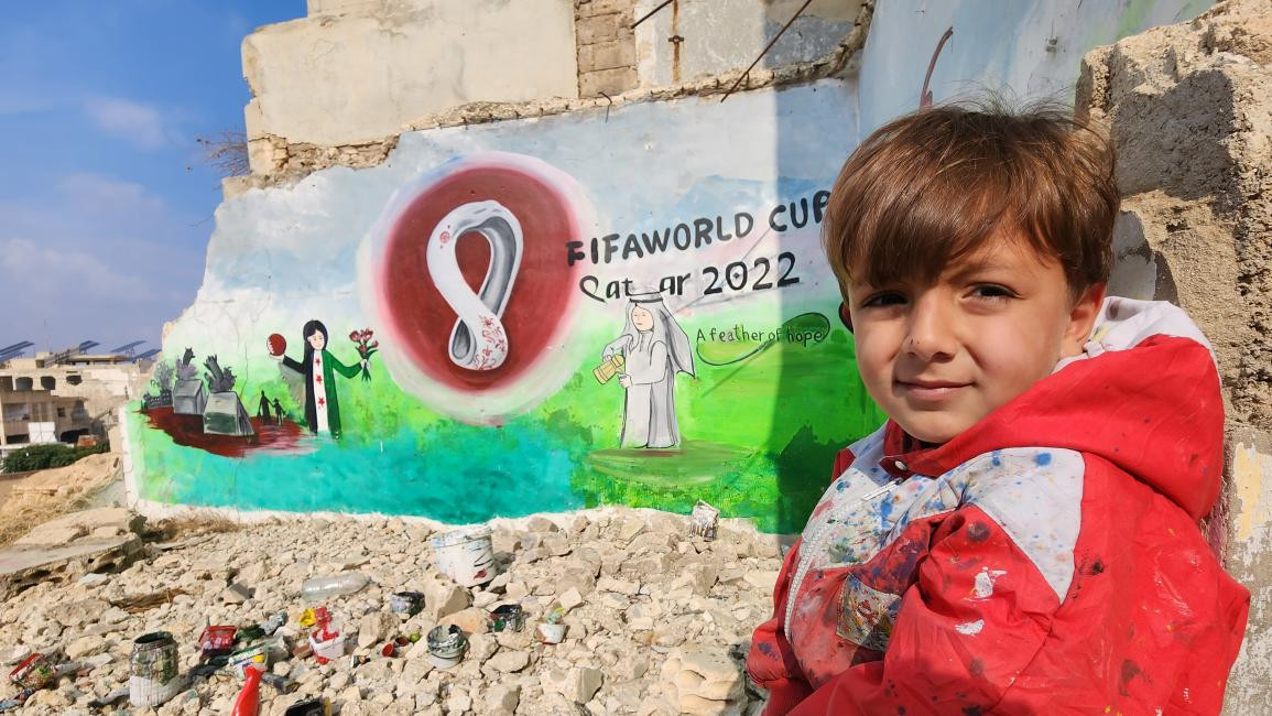 Boy next to wall art in Binnish, Idlib, for Qatar World Cup 