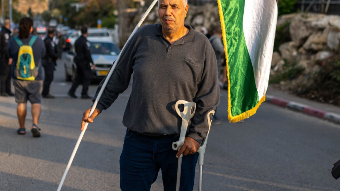 Muhammad abu-el-Humos holding the Palestinian flag in Sheikh Jarrah in occupied East Jerusalem