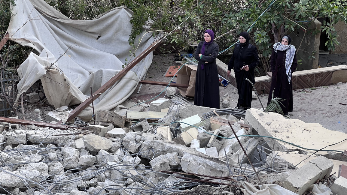 Women of the Beshir family stand upon the ruins of their home