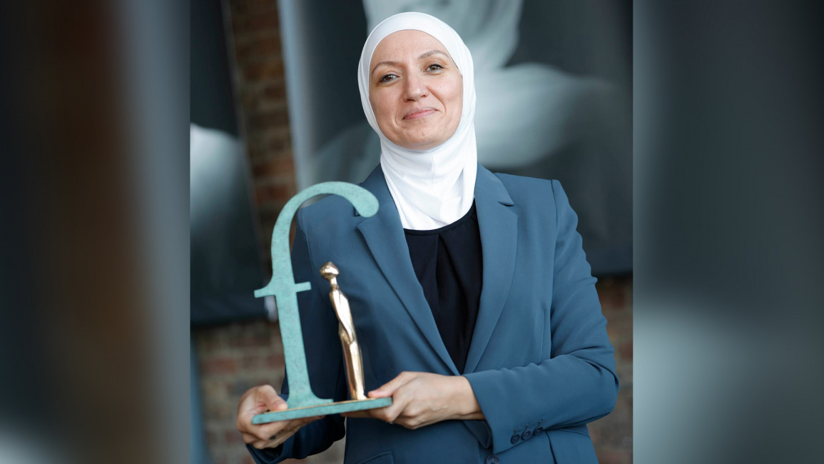 A picture of Jordanian human rights defender Hala al-Ahed holding an award up.