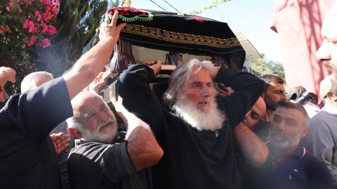 Mourners hoist the caskets of the four civilians killed by an Israeli airstrike on 6 October, at their funeral in the Lebanese border town of Blida. [William Christou - TNA].