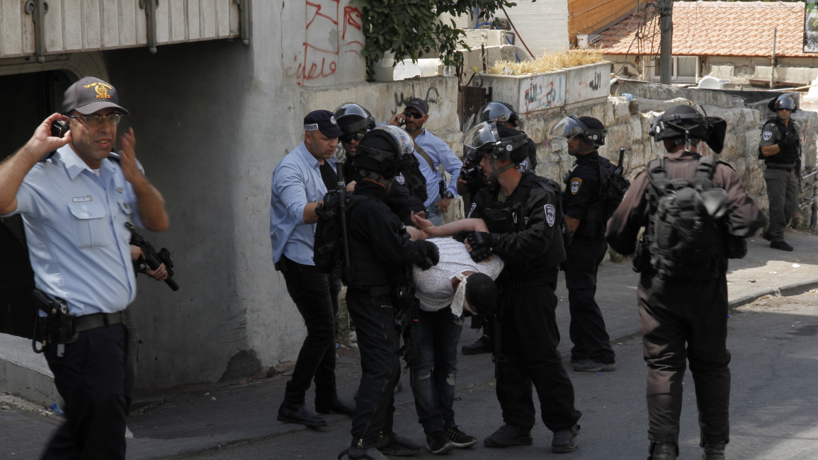Israeli police detaining a young Palestinian man