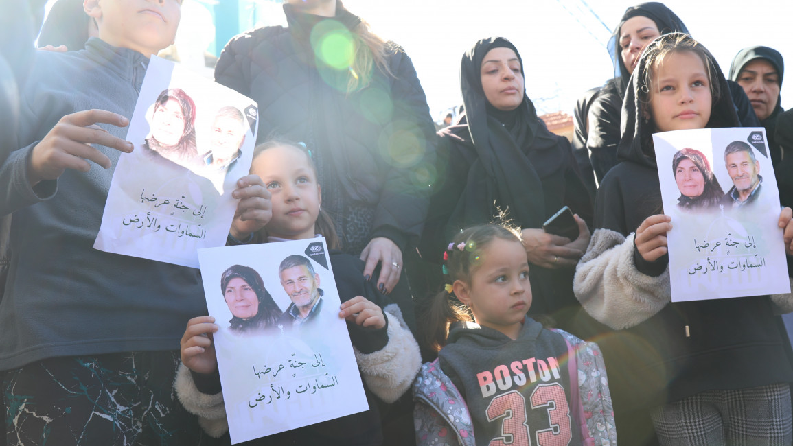 Hamdan and Abadi’s four grandchildren and daughter in law hold their portraits at their funerals in Kafra, south Lebanon. [William Christou – TNA].