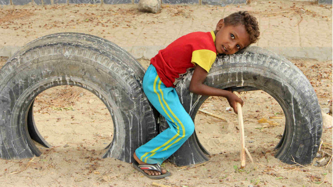 A Yemeni child plays on used car tyres