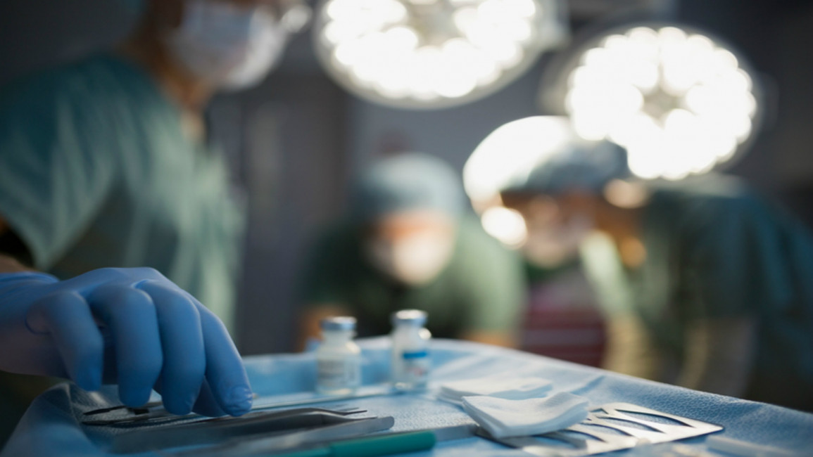  [Getty[Surgeon reaching for instrument on tray operating room