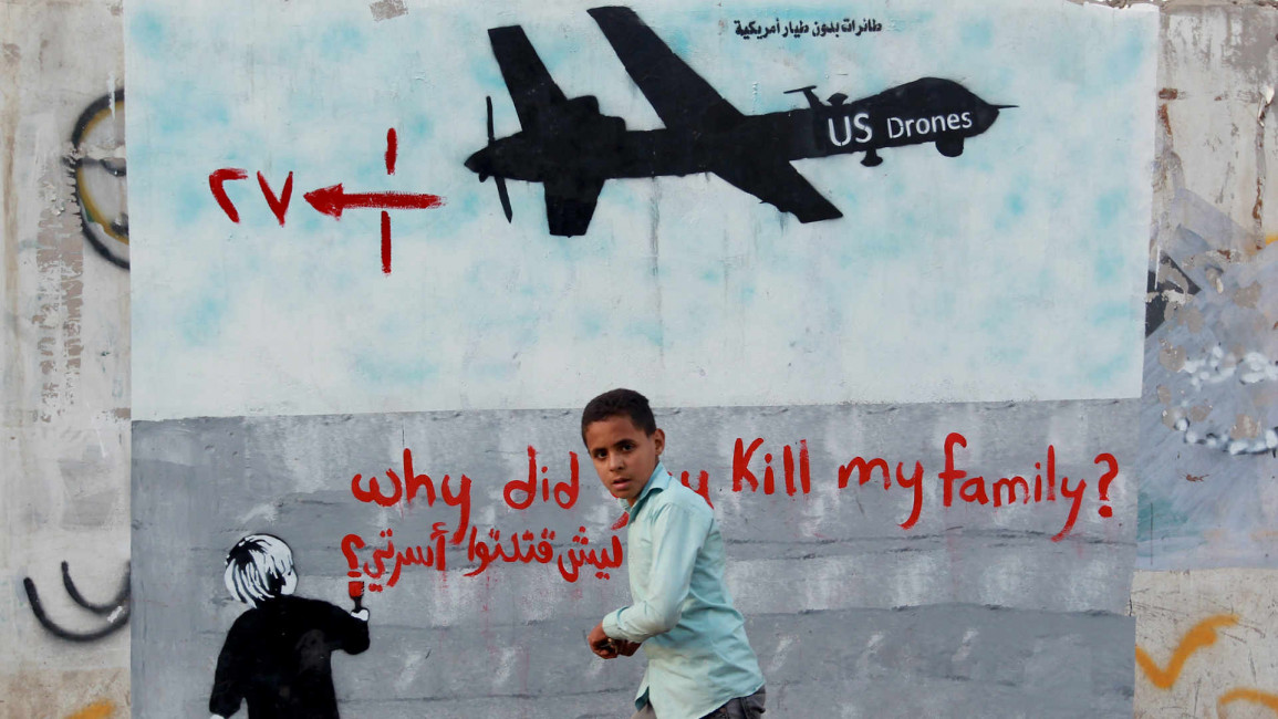 Yemeni boy walks past a mural in Sanaa