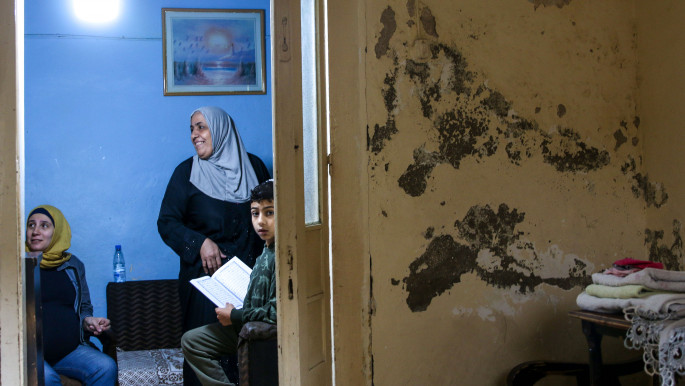 Salma el-Hendi and her family talk in their apartment, where one wall has been painted blue by Utopia, but the others are dilapidated and eaten away by humidity. Qalamoun, North Lebanon, 12 november 2022, Philippe Pernot