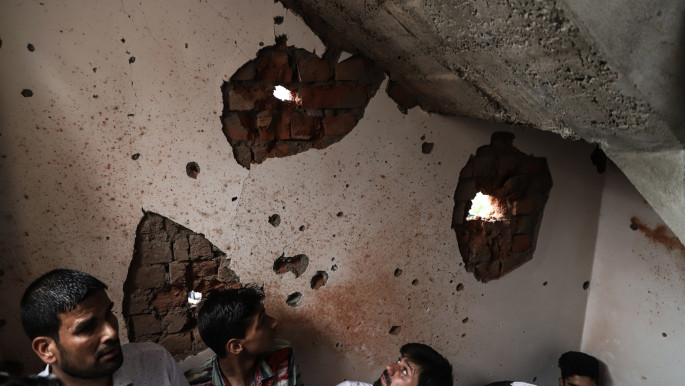 People inspect a house damaged during a gun battle in Srinagar, Indian-administered Kashmir 