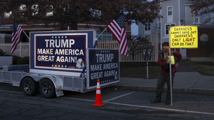 A protester stands beside a pro-Trump billboard  Portsmouth, New Hampshire 2015 [Getty]