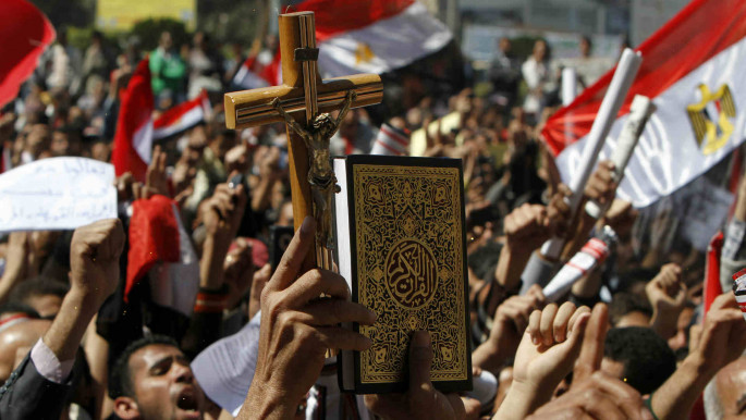 Protesters in Egypt's Tahrir Square hold up Qur'an and crucifix as sign of sectarian unity [Getty]