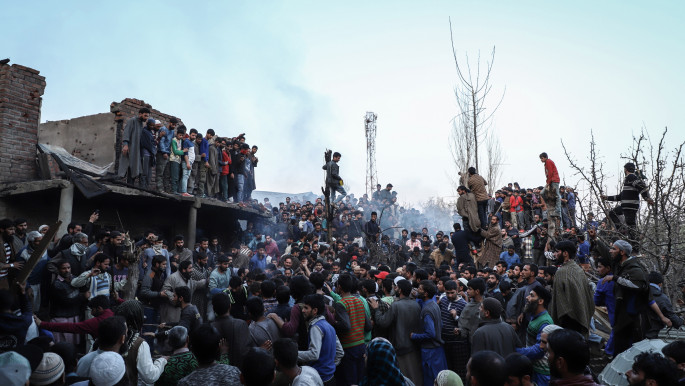 Kashmiri locals gather near damaged homes during a gun battle between rebels and government forces in Kachdoora village in Indian-administered Kashmir on 1 April, 2018.